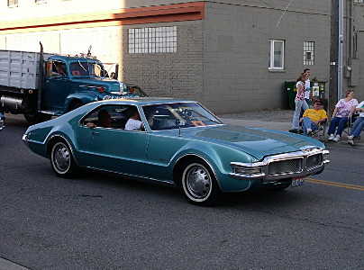 [A door-door aquamarine car with no visible headlights and hubcaps the same color as the car.]